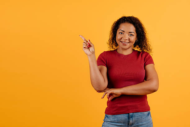 istock Young African American woman smiling, confidently pointing sideways with one hand 2207313932