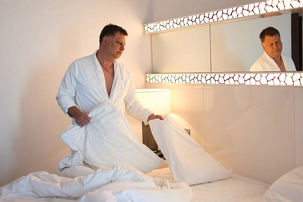 istock A mature man preparing for a restful night by fluffing his pillow, creating a cozy and inviting atmosphere in his bedroom, surrounded by soft lighting and a serene ambiance that promises a peaceful sleep and relaxation after a long day 2207315108