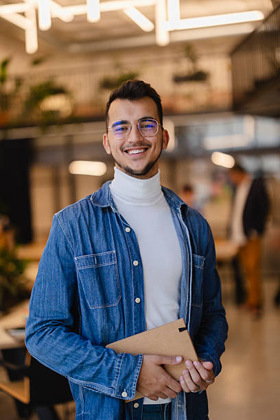 istock Young businessman smiling holding a notebook in a modern office 2207317963