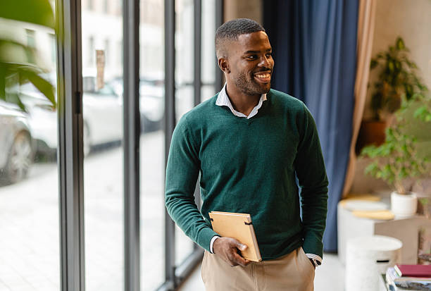 istock Young businessman smiling and holding a notebook in his modern office 2207317972