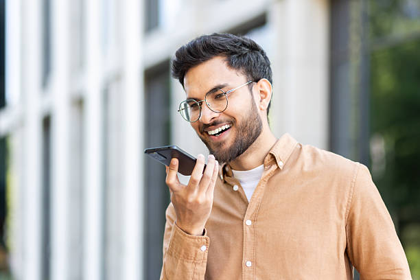 istock A college student with glasses smiles as he uses the voice command function on his smartphone outdoors on campus. 2207319212