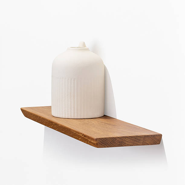 istock Ceramic vase on oak wooden shelf attached to white wall, design element, angle view 2207319214