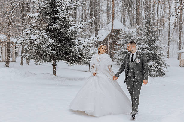 istock A bride and groom are walking through the snow in a forest 2207319834