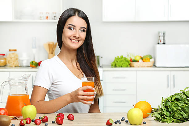 istock Beautiful young woman drinking juice in the kitchen 2207320251