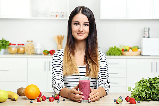 istock Beautiful young woman drinking smoothie in the kitchen 2207320697