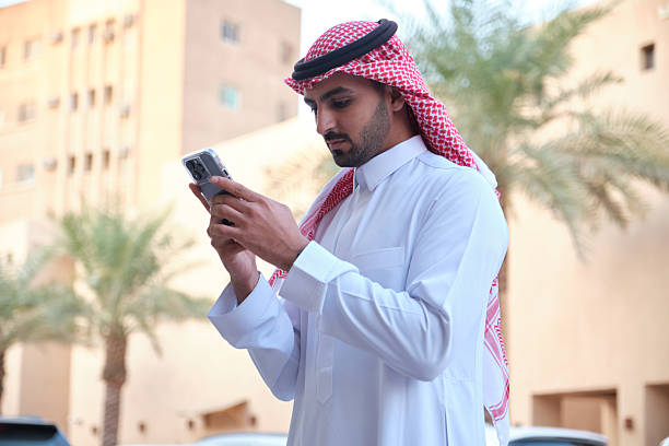 istock Saudi man in traditional clothing using Smartphone 2207321493