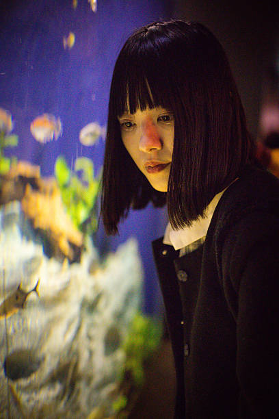 istock Woman looking at tropical fish in aquarium 2207321525