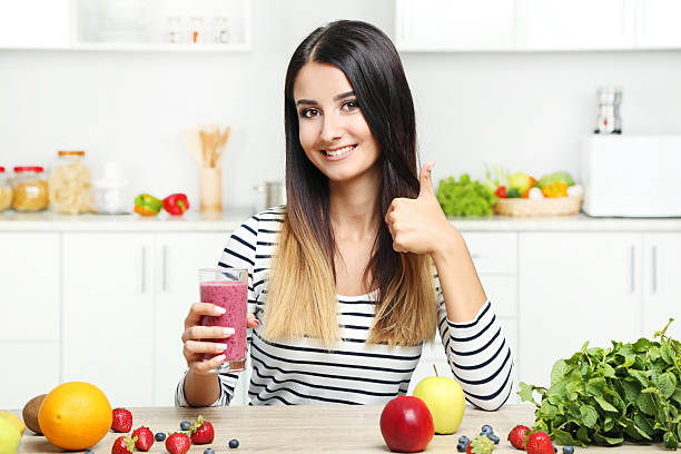 istock Beautiful young woman drinking smoothie in the kitchen 2207322297