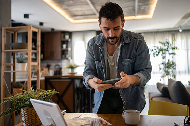 istock Focused man taking pictures of documents with his smartphone at home 2207323302