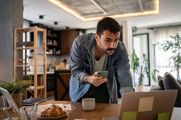 istock Focused freelancer comparing data from smartphone and laptop at home 2207323311