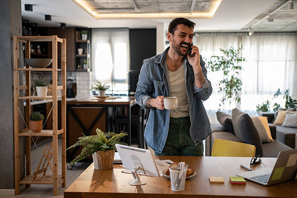 istock Freelancer enjoying a coffee while talking on the phone at home office 2207323324