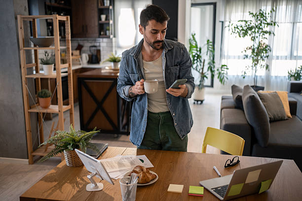 istock Freelancer enjoying morning coffee and checking smartphone at home office 2207323332