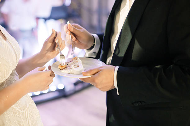 istock Wedding Cake Tradition – Bride and Groom Enjoying a Slice, Marriage Celebration 2207323955