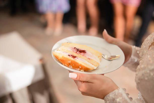 A mouthwatering slice of wedding cake with creamy frosting and fresh fruits, captured during the traditional cake cutting moment. While it's a sweet and indulgent treat, it's also a calorie-packed part of the celebration.