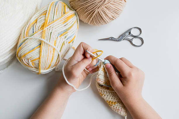istock Child crocheting with yarn and scissors on white table 2207326922