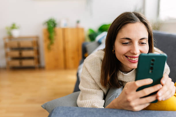 istock Young woman relaxing on sofa using smartphone at home 2207330572