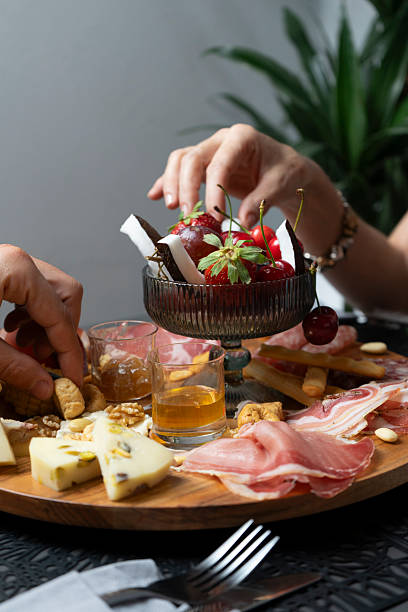 istock Hand taking a cherry from a platter of cold cuts, cheeses and fruit 2207332127