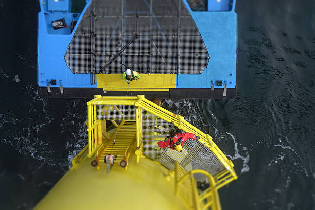 Transfer vessel pushing on landing ladder on large vessel, offshore platform and workers climbing on wind turbine