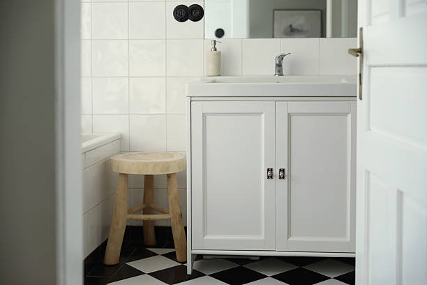 istock Retro style elegant bathroom interior through open door. Wash basin, cabinet, mirror. Marble soap dispenser. Black white checkered floor white tile wall background. Elegant minimal Scandinavian design 2207332601