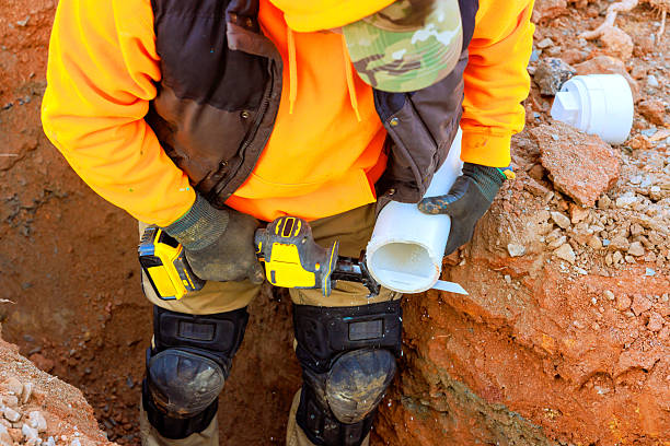 istock Worker installs plumbing in trench during construction project at outdoor site 2207333488
