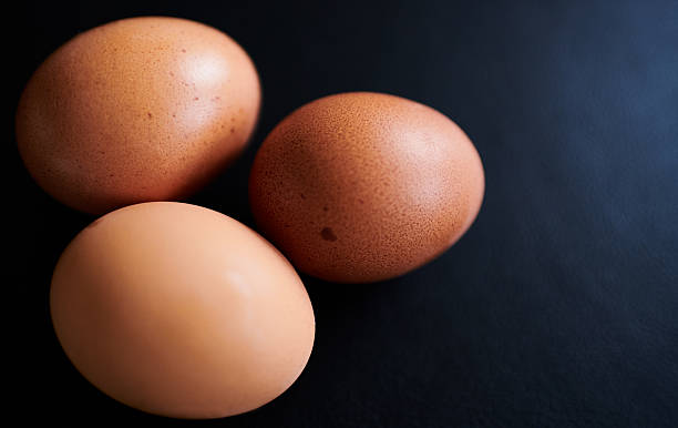 istock Close-Up of Brown Eggs on Dark Background 2207334135