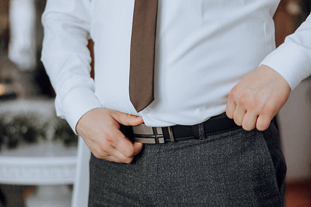 istock A man in a white shirt and a brown tie is adjusting his pants 2207337867
