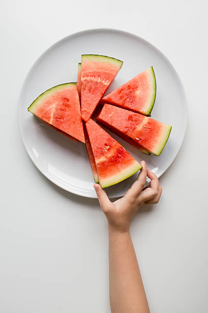 istock Child hand reaching for fresh watermelon slices on a plate 2207341298