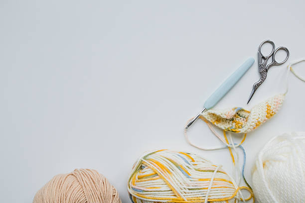 istock Knitting essentials with yarn balls, crochet hook, and scissors on white background 2207341341