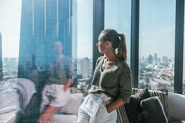 istock Woman Standing by Window Overlooking Cityscape 2207343237