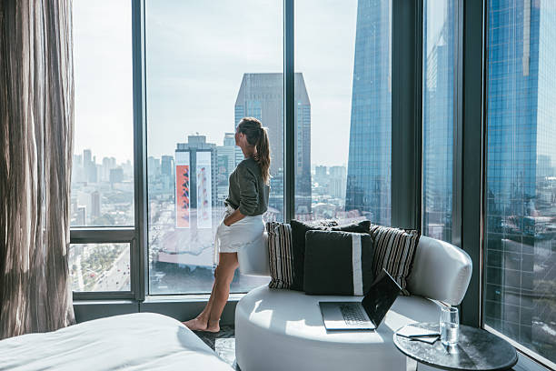 istock Woman Standing by Window Overlooking Cityscape 2207343247