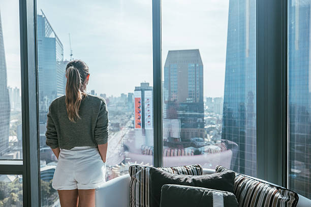 istock Woman Standing by Window Overlooking Cityscape 2207343296