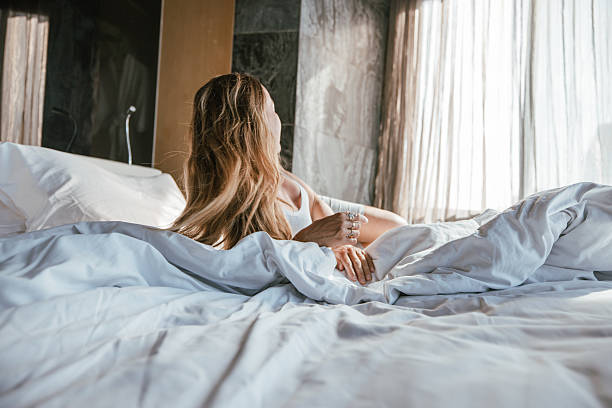 istock Woman relaxing on a bed in morning light. 2207343745