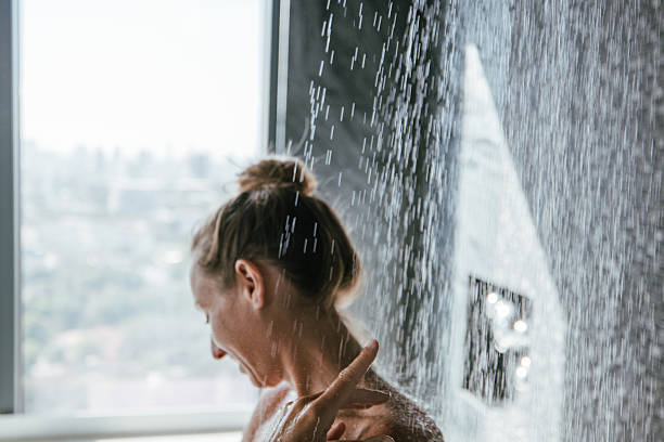istock Woman enjoying a refreshing shower with a city view. 2207343880