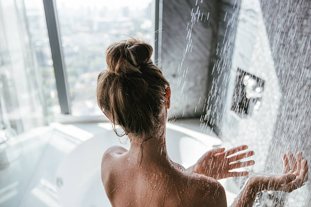 istock Woman enjoying a refreshing shower with a city view. 2207343982