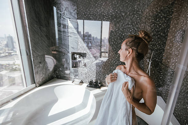 istock Smiling woman holding a towel in a luxurious bathroom. 2207344172