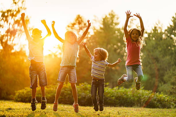 istock Children whit raised arms jumping in nature 2207351444