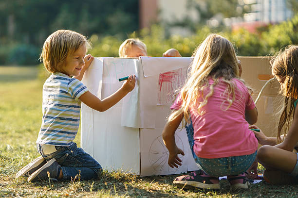 istock Children having fun drawing on carboard box in public park 2207352591