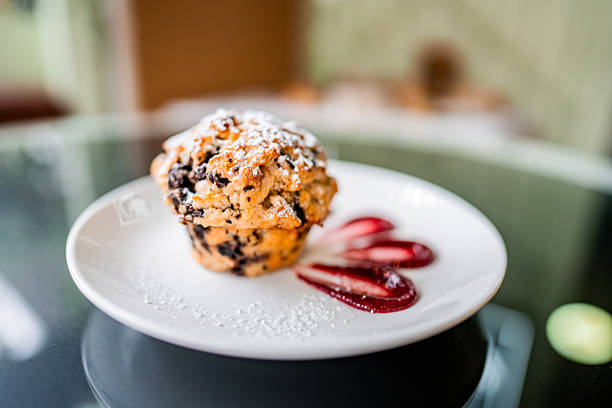 blueberry muffin and fresh scattered blueberries with on a dark surface.
