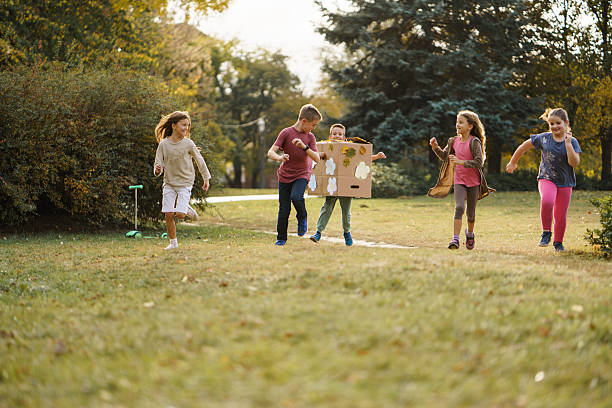 Happy boy whit carboard box and his friends having fun in public park during an autumn day