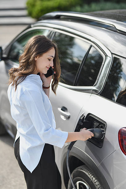 istock Cheerful Woman Charging Her EV and Having Friendly Phone Conversation 2207353302