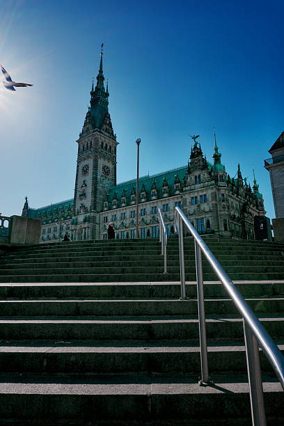 Staircase leading up to Hamburg Town Hall with a bright blue sky in the background, showcasing historic architecture and an inviting urban perspective