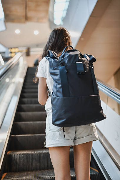 istock Young Woman With Backpack Riding Escalator in Bright Modern Building 2207355177