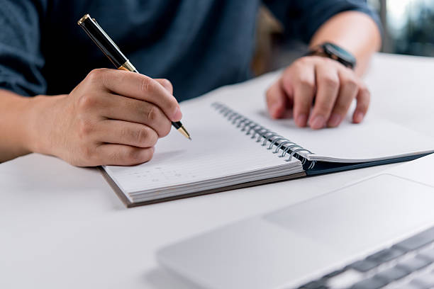 istock Hand writing on spiral notebook with pen and laptop, concept of education, online learning, planning, productivity, and personal development. 2207356692