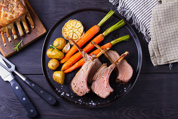 istock Roasted rack of lamb. Lamb chops with vegetables on black plate 2207356888
