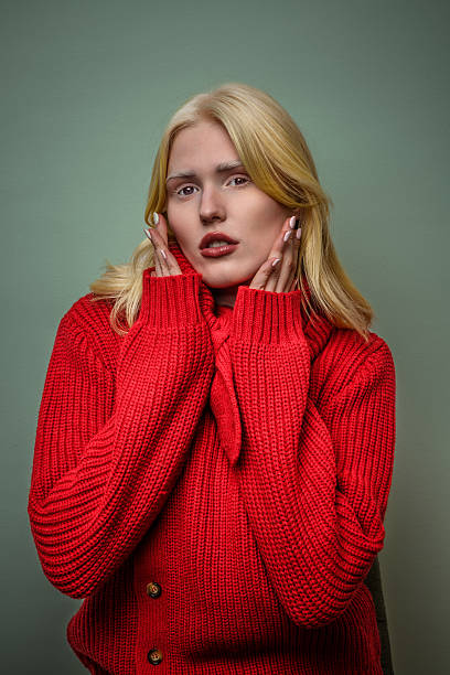 istock Model posing in a vibrant red sweater against a muted green backdrop 2207357782