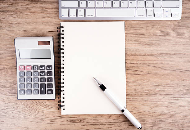 Flat lay view of keypad, empty notebook,calculator and a pen.