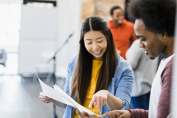 istock Two young adults reviewing documents together, smiling 2207360797