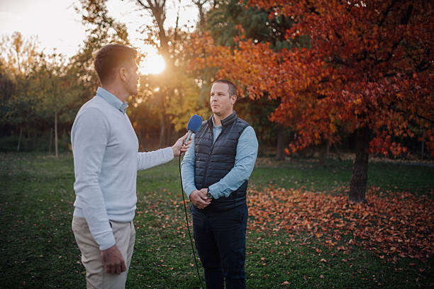 istock Journalist interviewing businessman in autumn park at sunset 2207361778