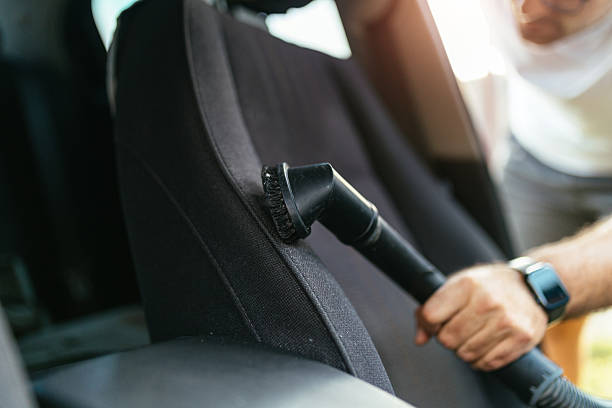 istock Man Vacuuming Car Seat Interior with Vacuum Cleaner in Sunlight 2207366751