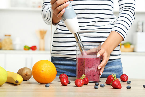 istock Young woman cooking smoothie in blender 2207370774
